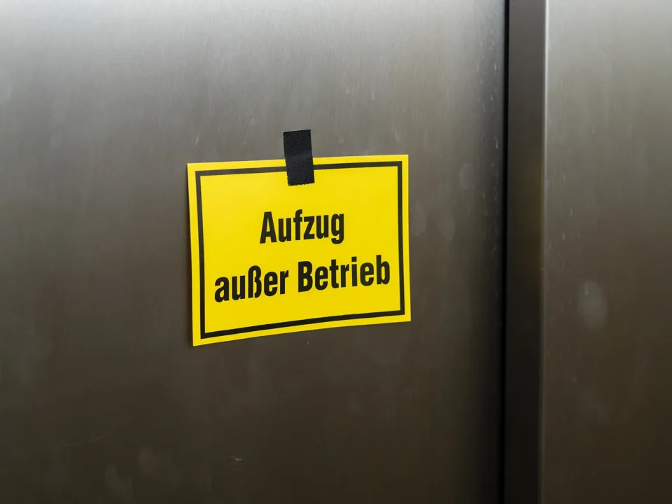 Gelbes Schild mit Aufschrift Aufzug außer Betrieb an geschlossener Aufzugstür